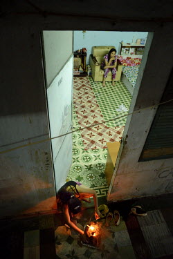 A man cooks on a brazier in the doorway of the room where he lives with his wife in the former Le President Hotel on Tran Hung Dao Street. It was used by the American military during the 1960s up unti...