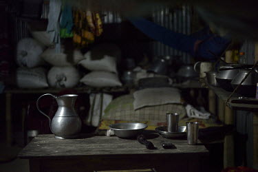 A mobile phone and a torch sit on a table among aluminium plates and cups. A rural electrification program, using solar panels, means the residents of the house will no longer have to buy expensive ba...
