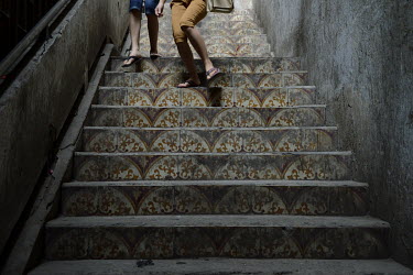 People walk down a stairway decorated with cement tiles in the former Le President Hotel which was used by the American military in the 1960s up until the evacuation of 1975. Many of the rooms in the...