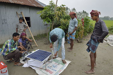 Technicians install a solar power system at a house built on Kharzanir, an island on the Jamuna River. These islands come and go over a period of around 10 to 20 years and thus connecting them to the...