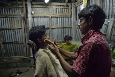 A man gets a shave at a barber's shop on Narayanpur, an island on the Jamuna River, which is powered by solar energy.