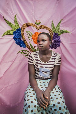 Grace Monia (13) in front of her Milaya (a traditional hand-decorated sheet) in the Bidibidi refugee settlement where she lives with her foster mother Rona. She was separated from her parents as they...