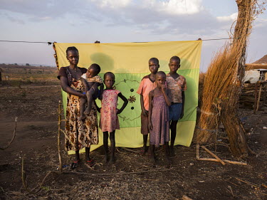 Rose Ozima (30) with her children and two of her brother-in-law's children standing in front of her Milaya (a traditional hand-decorated sheet) in the Bidibidi refugee settlement. "My husband was work...