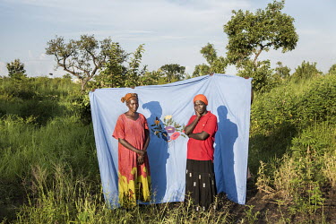 Elisabeth Sadia (37) and Joyce Aba (42) in front of a Milaya (a traditional hand-decorated sheet) in the Bidibidi refugee settlement. Elisabeth says: "I arrived here in December 2016 and came with my...