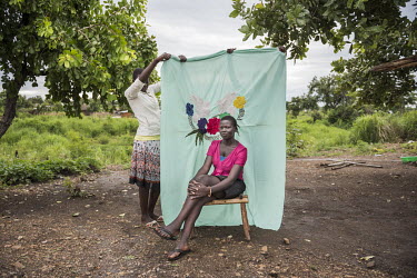 Florence Dusman (18) from Mukaya in South Sudan in front of her Milaya (a traditional hand-decorated sheet) at the Bidibidi refugee settlement where she lives with her stepfather and her brothers and...