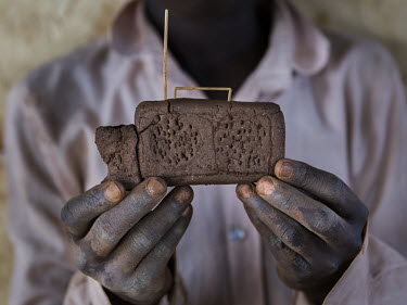 A South Sudanese refugee boy holds up the clay toy radio her made in Bidibidi refugee settlement.