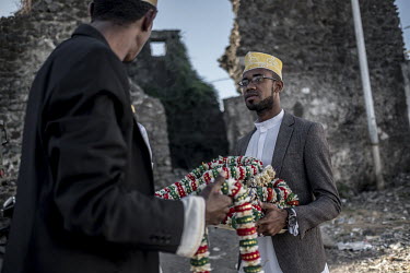 A man hands out garlands to wedding guests during the 'Madjiliss' ceremony in front of the crumbling remains of an old fortified building in the town's medina.