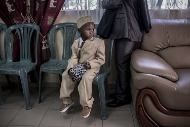 A boy dressed for a wedding ceremony sits during an event at the house of the bride during the early days of a traditional two week wedding.