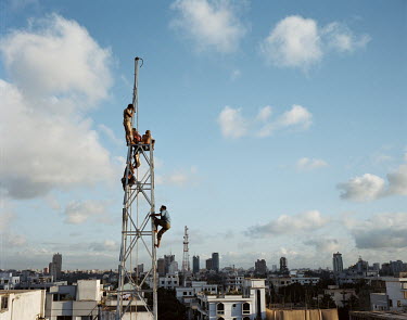 Workers construct a mobile communications transmitter tower.