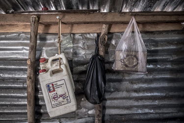 Old motor oil containers and a copy of the Koran hang from a wooden beam at a ylang ylang distillery. The oil distilled from the ylang ylang flower is a key ingredient in luxury perfumes and some cosm...