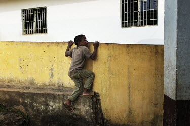 An boy climbs a wall to check if lunch is ready at the Notre Dame orphanage and school.