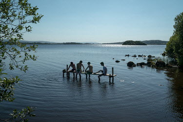 Teenage boys, three from the Republic and one from the North, relax on a makeshift jetty in Lough Erne, a few hundred metres from the border between the United Kingdom and the Republic of Ireland.