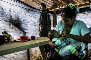A colleague stands behind Alejandra (32) as she breastfeeds her baby. The former FARC guerrilla gave birth alone in her tent a few months after hostilities ended. Alejandra was three months pregnant w...