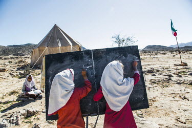 Two girls stand side-by-side writing on a blackboard at the Mostafa Reihani school where Bakhtiari nomad children receive primary education in the mountains to acquire basic literacy and numeracy skil...