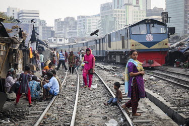 A train passes through a slum built beside a railway line where the residents go about their daily business seemingly oblivious to the danger.