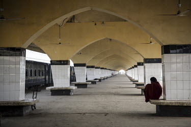 A man sits on a railway platform.