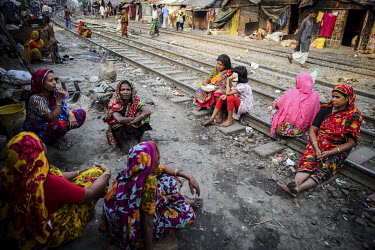 A group of women, living in a slum beside a railway line, sit and talk while they sit on the railway tracks.