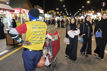 A porter with a trolly full of shopping waits for his employer in the Global Village, a massive shopping and entertainment complex.
