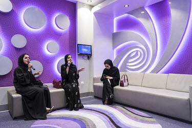 Three Emirati women singing karaoke at Hub Zero, an entertainment complex and fully interactive gaming park in the City Walk shopping mall.