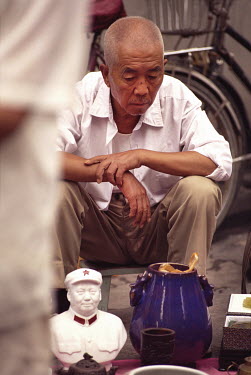A man selling Mao-era bric-a-brac in a flea market.