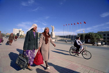 Two women walk past a giant statue of Chairman Mao in the city centre.