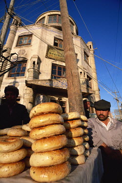 A Uygur man selling typical bagel-shaped bread from a street stall.