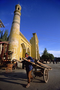 A Uygur man pulls a hand cart past the Id Kah Mosque.