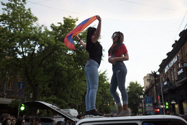 Two women wave the national flag from a car roof as people celebrate in Republic Square after hearing that Prime Minister Sargsyan announced his resignation following mass protests at his move from pr...