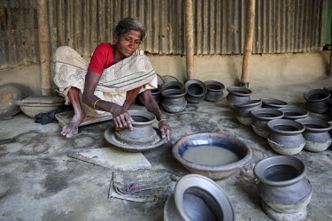 A woman making a pot at one of the many artisan pottery businesses in Dhamrai.