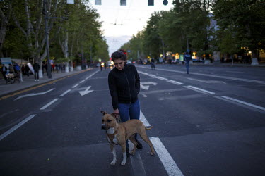 A woman and her dog crossing a road.