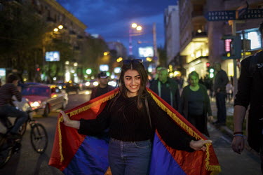 A woman drapes the national flag around her shoulders as people celebrate in Republic Square after hearing that Prime Minister Sargsyan announced his resignation following mass protests at his move fr...