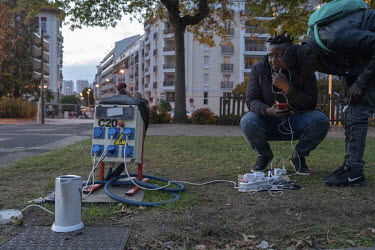 Migrants charge their mobile phones at an electricity point that the city of Bayonne has provided in the Place des Basques.