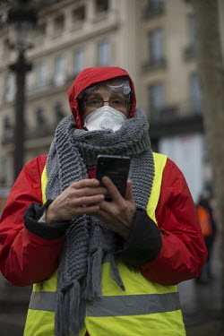 An anti government protester attached to the 'Gilet Jaunes' movement holds a mobile phone at a demonstration in Paris.   Starting on 17 November 2018, protesters wearing yellow vests ( gilets jaunes...