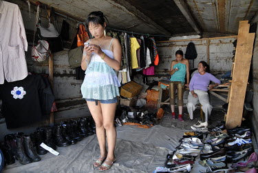 Two women check their mobile phones in a clothing stall located in a former container in the town's market.