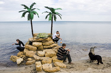 People making mobile phone calls from a fake plastic island used as a background by a beach photographer in Russian anexed Crimea.