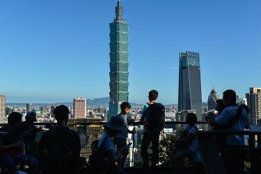 People at a view point on Four Beasts Mountain overlooking the city and the prominent Taipei101 Tower.
