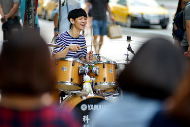 A busker playing a set of drums draws a crowd in the Xinyi District.