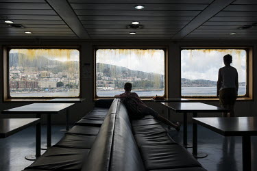 Two passengers look out of the window of the ferry boat as it approaches the city of Messina after crossing the Strait of Messina.