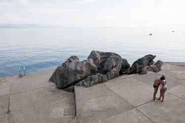 A couple embrace on a concrete water front on the Lungomare, the historical seaside promenade on the Adriatic coast, which runs over 12 km from Lovran to Volosko.