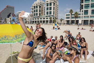 A young woman making a selfie with her friends on the beach in Tel Aviv.