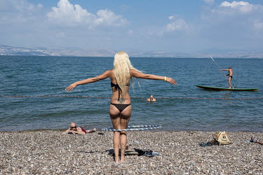 A woman with a hoolahoop on the beach of the Sea of Galilee.
