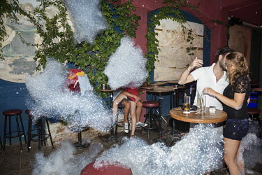 Couples at a foam party at a bar.