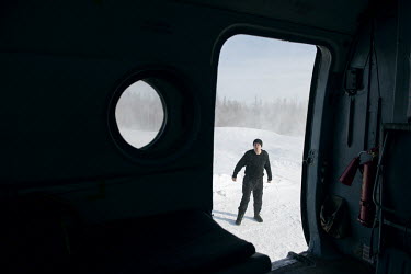 The onboard mechanic helps the pilot make a correct landing at a remote snow-covered landing site where they have come to collect a patient and transport them to hospital.