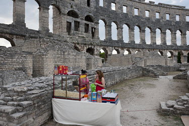 Women selling popcorn from a stall at the Pula Arena, a Roman amphitheatre on the coast, still being used for concerts and cultural events.