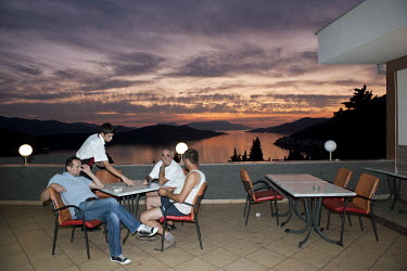 A waiter clears a table at a seaside restaurant as the sun sets beyond the bay of Neum, the only coastal town in Bosnia and Herzegovina. It comprises 24.5 km of coastline, the country's only access to...