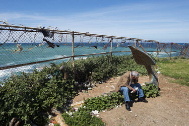 A man takes a rest on an anchor on the Mediterranean shore.