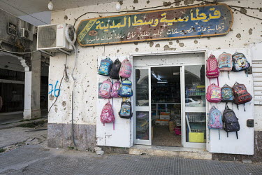 A shop pock marked with shell fragments selling school children's bags and other items for school.