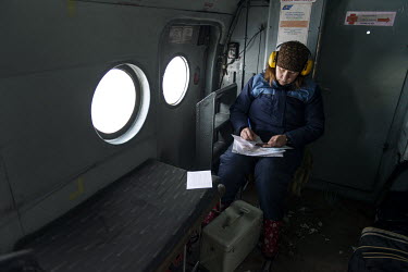 Anna, a medic, fills out documents during a helicopter flight from Vankor to Turukhansk.
