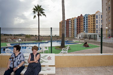 Two women rest on a bench in a resort on the Mediterranean coast.