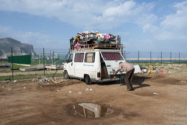 A Tunisian rag and bone man prepares his overloaded van for the ferry back home. He collected second hand and recycable things in Sicily, to export and sell in Tunisia.